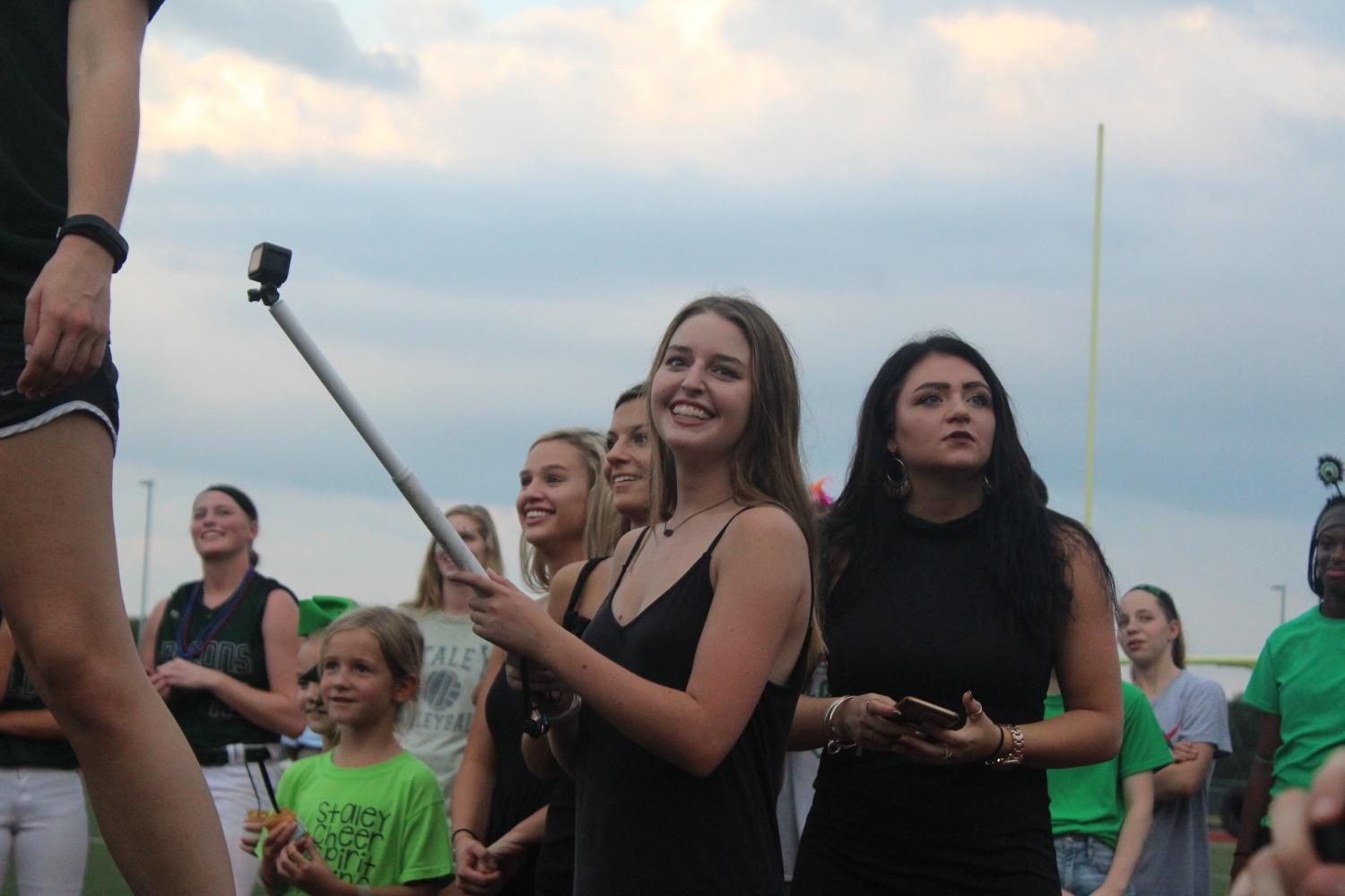 Filming for her next hype video at the pep rally on Sept. 20, junior Pierson Beaulieu records the students yelling a chant. She normally recorded the student section, cheerleaders, Emeralds and players during games. “I hope to make more videos for other sports,” said Beaulieu.