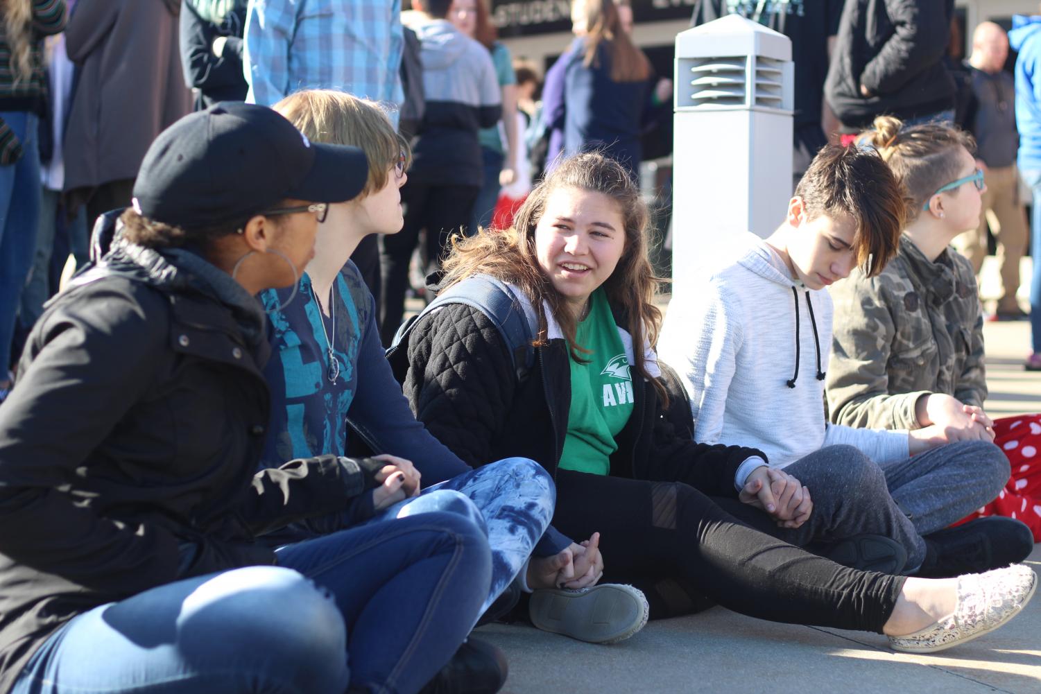 While participating in the walkout on March 14, sophomores Lexi Valdez, Naomi Davis, Maria Engemann, Tanner Sneed and Shayla Crumb-Potmesil sit and hold hands out of respect for the 17 victims of the Parkland, Fla., school shooting. #NationalWalkoutDay was trending globally on Twitter to cover all the walkouts across the country. “We wanted to sit down to make it better because everyone else was standing and talking and laughing, instead of paying attention to the ones who passed away,